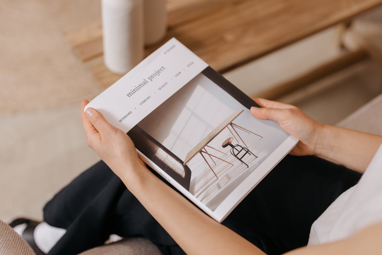 Person relaxing indoors while reading a minimalist design magazine, showcasing modern aesthetics.