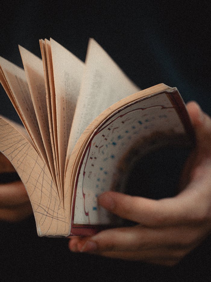 Artistic view of hands flipping through an illustrated sketchbook with unique designs.